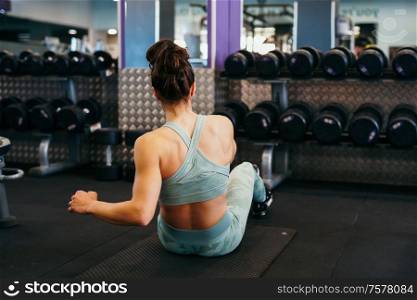 Young sportswoman wearing sportswear, on yoga mat doing situps in gym. Fitness woman doing abs crunches.. Sporty young female on yoga mat doing situps in gym.
