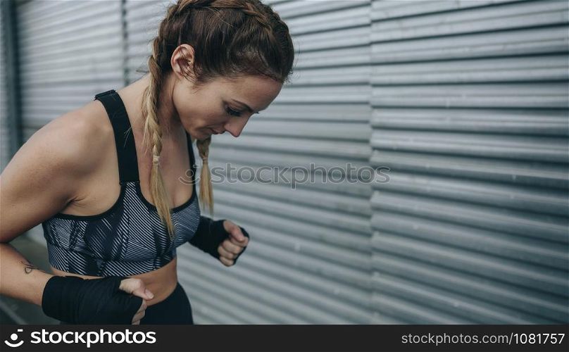Young sportswoman with boxing bandages concentrated to train outdoors. Sportswoman concentrated to train