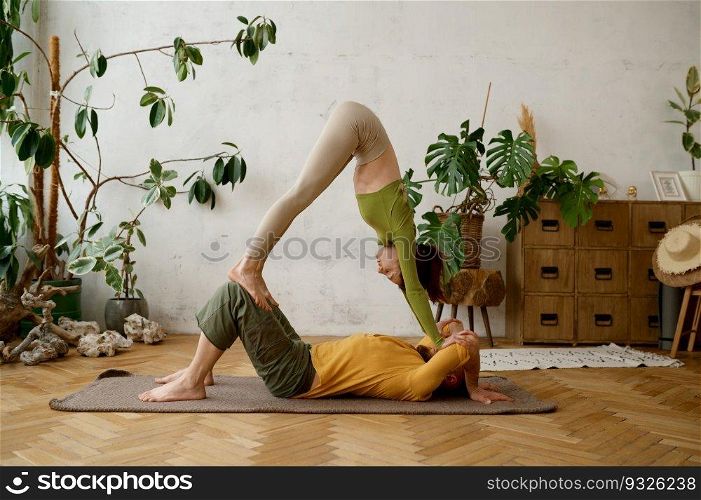 Young sporty couple practicing yoga lesson doing asana together indoor at light room. Healthy lifestyle and relationships concept. Young sporty couple practicing yoga lesson at light room