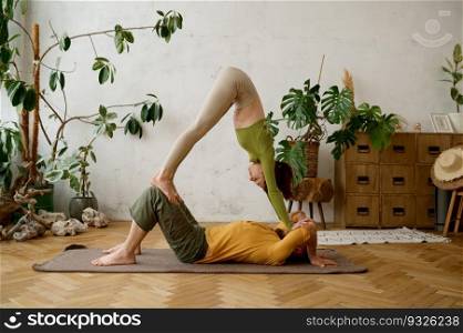 Young sporty couple practicing yoga lesson doing asana together indoor at light room. Healthy lifestyle and relationships concept. Young sporty couple practicing yoga lesson at light room