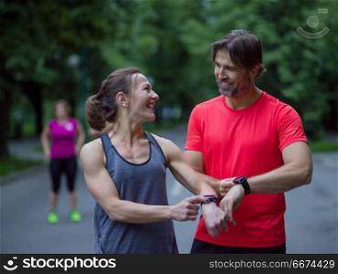 Young sporty couple using smart watches starting their timer before jogging. sporty couple using smart watches
