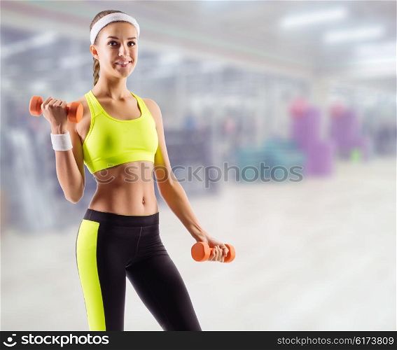 Young sporty girl with dumbbells in fitness club
