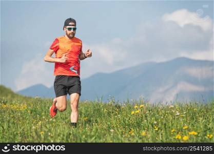Young sporty man runs through the meadows
