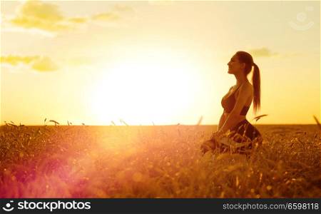 Young sporty woman at sunset in wheat field