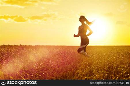 Young sporty woman at sunset in wheat field