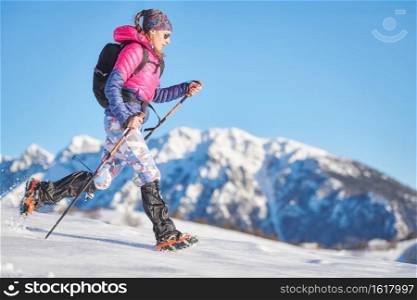 Young sporty woman in the snow with cr&ons and gaiters