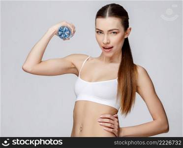 young sporty woman over gray background drinking water. sporty woman over gray background drinking water