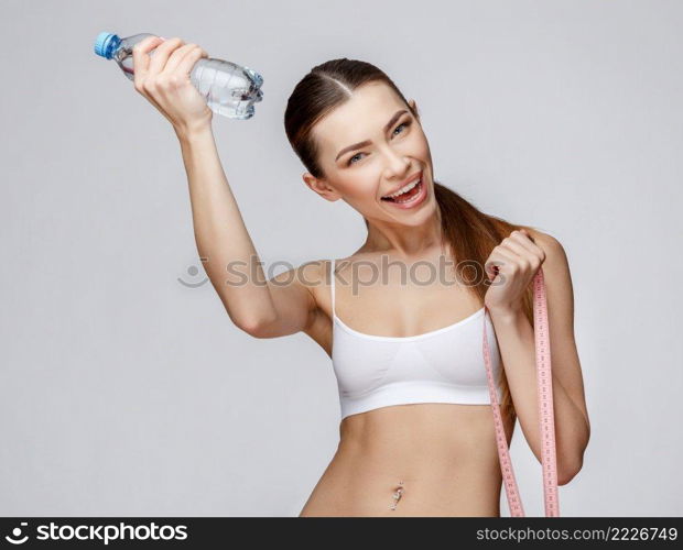 young sporty woman over gray background drinking water. sporty woman over gray background drinking water