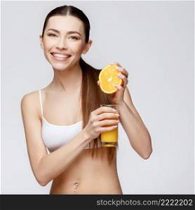 young sporty woman over gray background holding glass of orange juice. sporty woman over gray background holding glass of orange juice