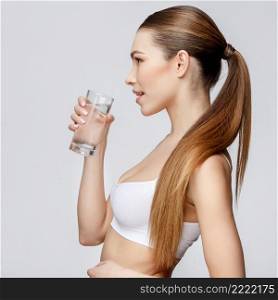 young sporty woman over gray background holding glass of water. sporty woman over gray background holding glass of water