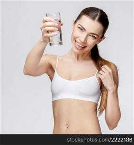 young sporty woman over gray background holding glass of water. sporty woman over gray background holding glass of water