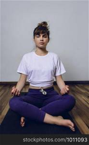 Young sporty woman practicing yoga doing Half Lotus pose with mudra, indoors. Healthy lifestyle concept.