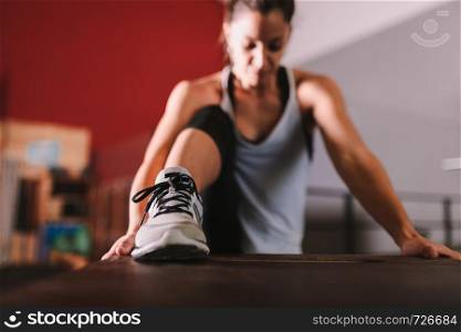 Young sporty woman stretching in interior before exercise
