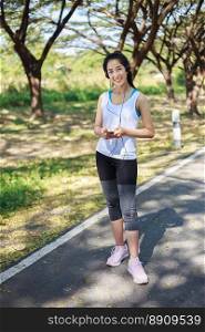 young sporty woman using smartphone with headphone in the park