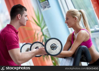 young sporty woman with trainer exercise weights lifting in fitness gym