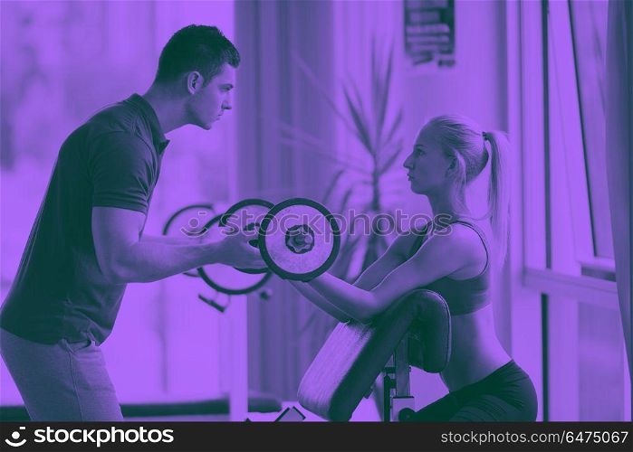 young sporty woman with trainer exercise weights lifting in fitness gym duo tone. young sporty woman with trainer exercise weights lifting