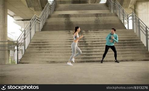 Young sporty woman with trainer exercising in urban enviroment