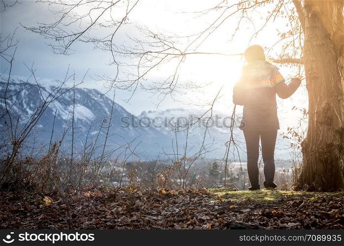 Young standing girl is enjoying the sunset scenery, winter time