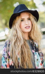 Young staring woman wearing jacket and hat, happy in urban background