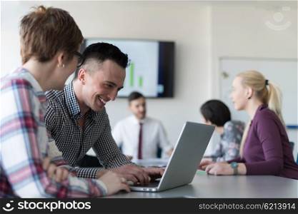 young startup business people, couple working on laptop computer, businesspeople group on meeting in background at office interior