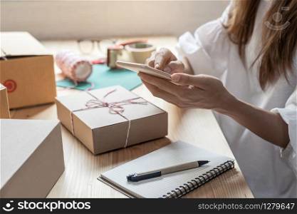 Young startup small business entrepreneur woman working with smart phone at home, Online business and delivery concept. Young entrepreneur woman working at home