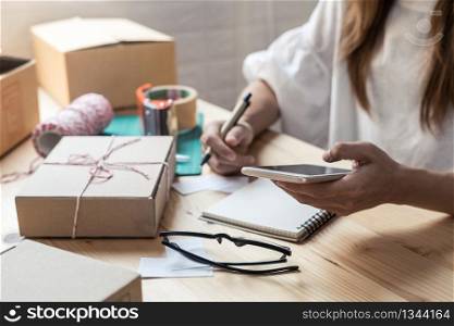 Young startup small business entrepreneur woman working with smart phone at home, Online business and delivery concept. Young entrepreneur woman working at home