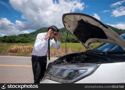 Young stressed man having trouble with his broken car looking in frustration at failed engine.