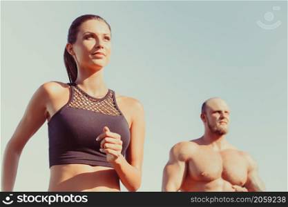 Young strong male and female fitness models outdoors in beautiful landscape. Man and woman running in park close up. Man and woman running in park