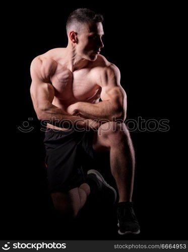 Young strong man isolated on black