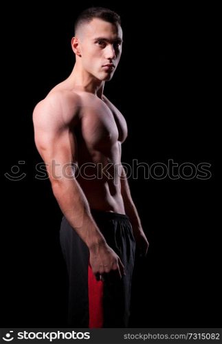 Young strong man isolated on black
