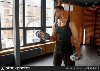 Young strong man training with dumbbells weights at sport gym. Sport, bodybuilding and workout concept. Man training with dumbbells at sport gym