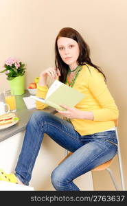 Young student girl reading book in student apartment