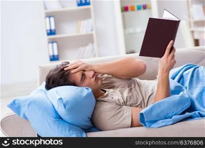 Young student man preparing for college exams in bed with book
