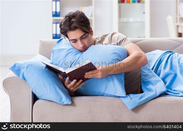 Young student man preparing for college exams in bed with book