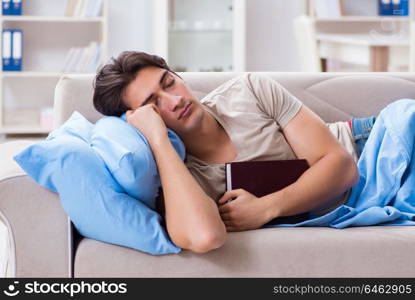 Young student man preparing for college exams in bed with book