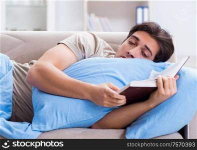 Young student man preparing for college exams in bed with book. The young student man preparing for college exams in bed with bo