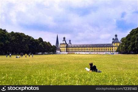 Young student resting on the grass reading a book in Bonn, Germany.. Young student resting on the grass reading a book