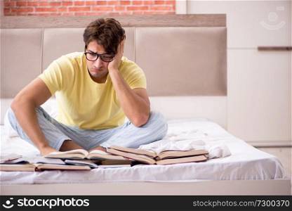 Young student studying in bed for exams