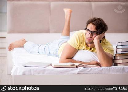 Young student studying in bed for exams
