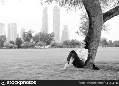 Young student woman reading a book and study in the park