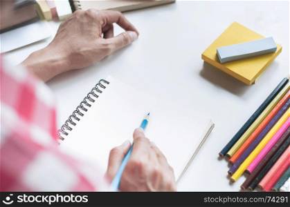 Young student woman writing on notebook, doing home work on the desk