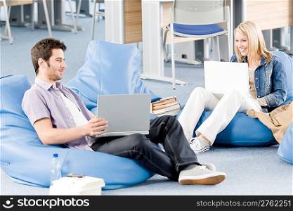 Young students at high-school relaxing pointing at laptop