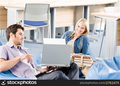 Young students at high-school relaxing pointing at laptop