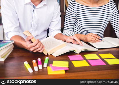 Young students classmates help friend catching up workbook and learning tutoring in a library, education and school concept.