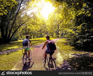 Young students riding their bikes on Rheinaue park, Bonn, Germany.. Young students riding their bikes on a park