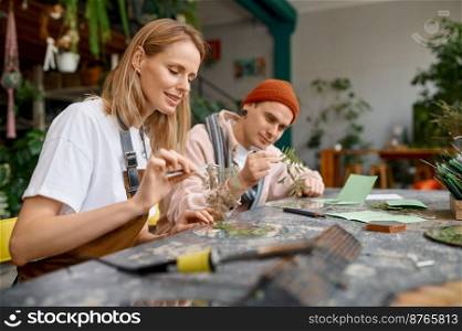 Young students studying at craft workshop. Man and woman creative artist making floral decoration for design interior. Young creative artists studying at craft workshop