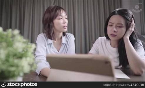 Young students watching online lesson and studying from home, Asian women having a discussion on homework together, good teamwork brainstorming, using wireless technology or digital tablet,