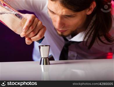 Young stylish man bartender preparing serving alcohol cocktail drink, pouring vodka filling a jigger