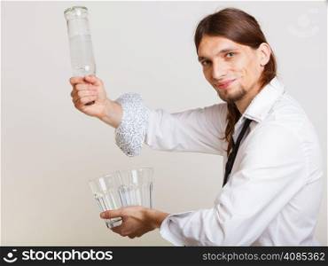 Young stylish man bartender with bottle alcohol pouring a drink studio shot on gray