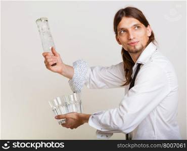 Young stylish man bartender with bottle alcohol pouring a drink studio shot on gray